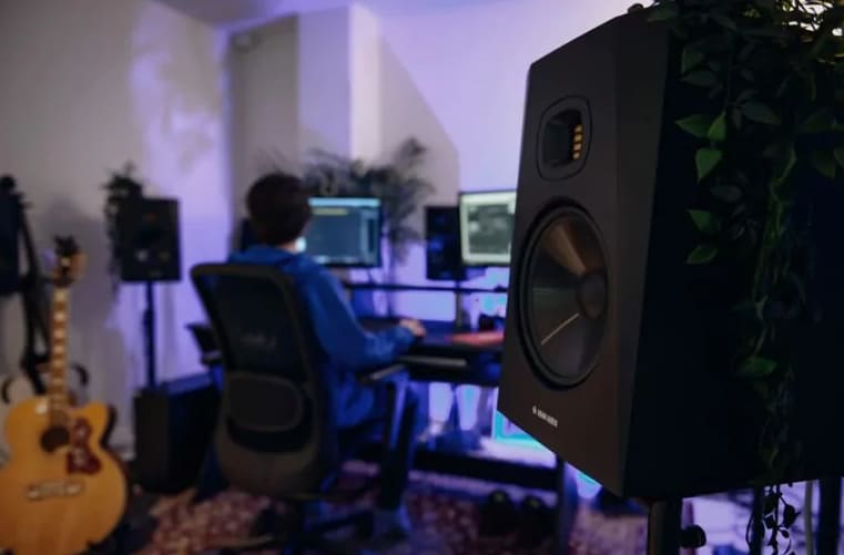 Adam Audio T8V in a studio with someone working in the background.