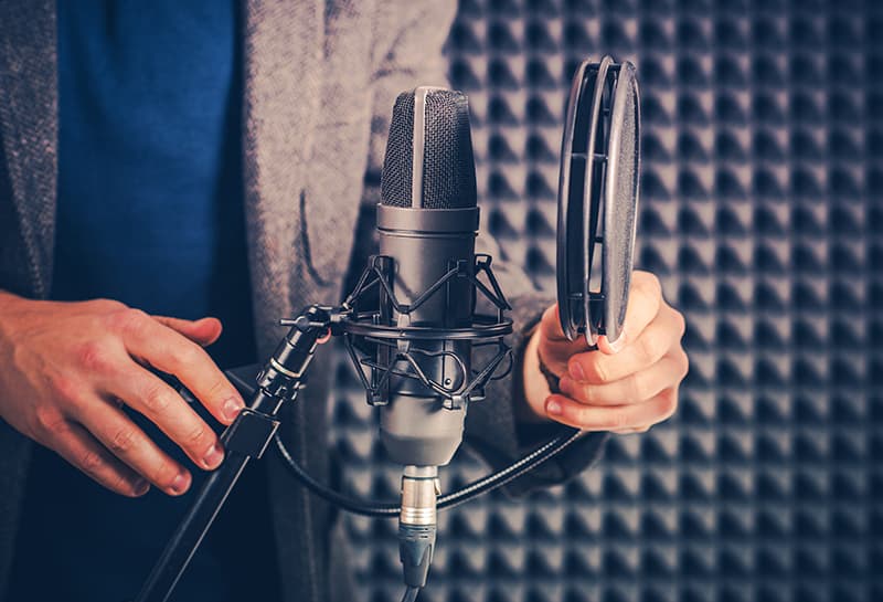 Microphone with a pop filter with acoustic foam in the background.
