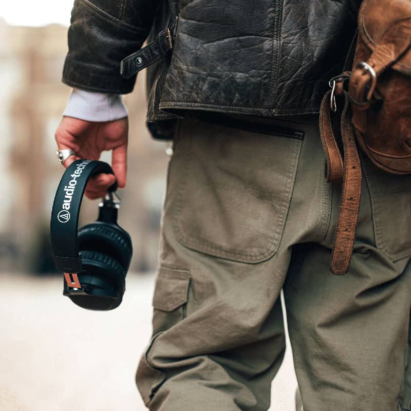Man holding a pair of Audio-Technica ATH-M20xBT headphones.