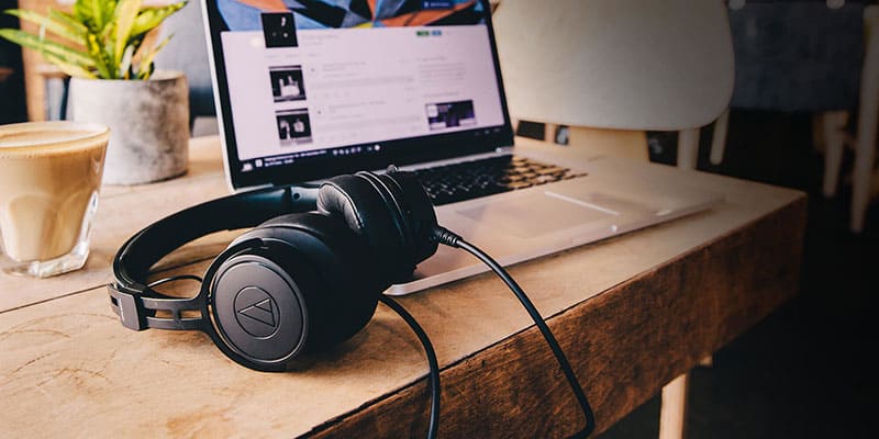 Audio-Technica ATH-M60x headphones on a wooden desk with a laptop in the background.