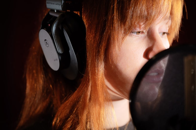 Woman wearing Austrian Audio Hi-X55 in a recording studio.