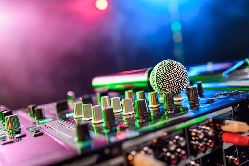 Photo of a microphone sitting on top of a DJ mixer.