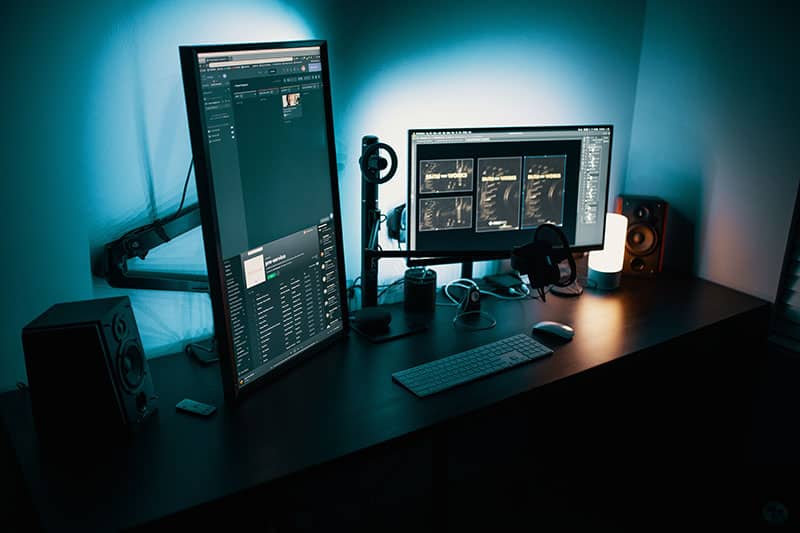 A podcast editing station with two screens and studio monitors.
