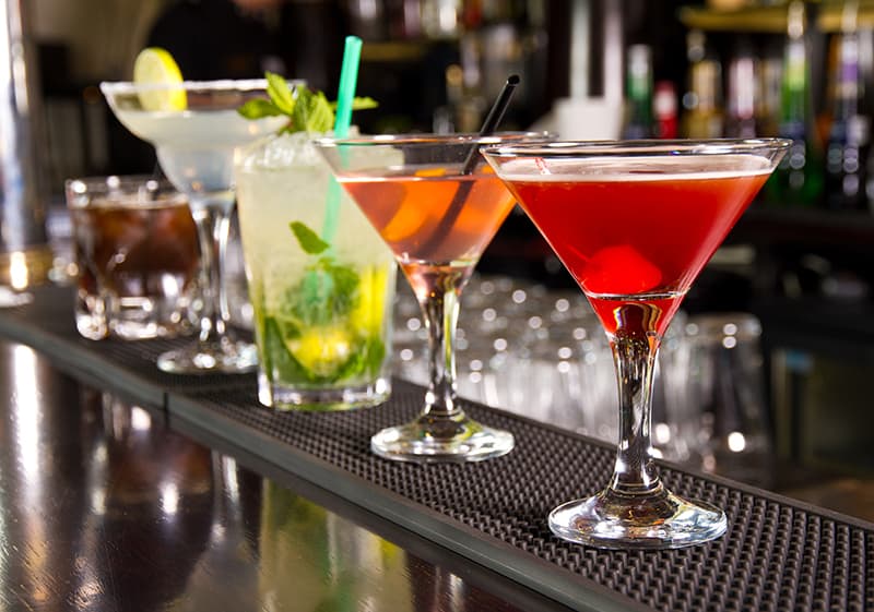 A row of cocktails on a bar.