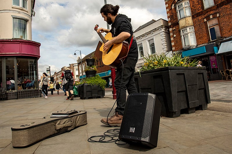 Man busking with a guitar connected to an EV Everse 8.