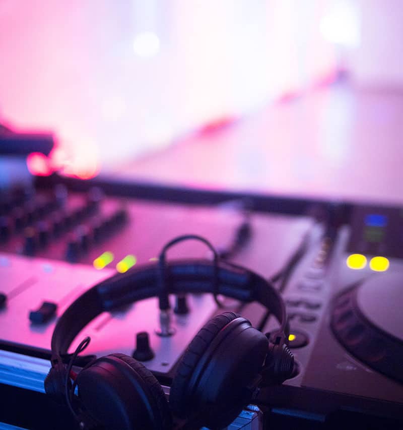 DJ equipment in front of a brightly lit dancefloor