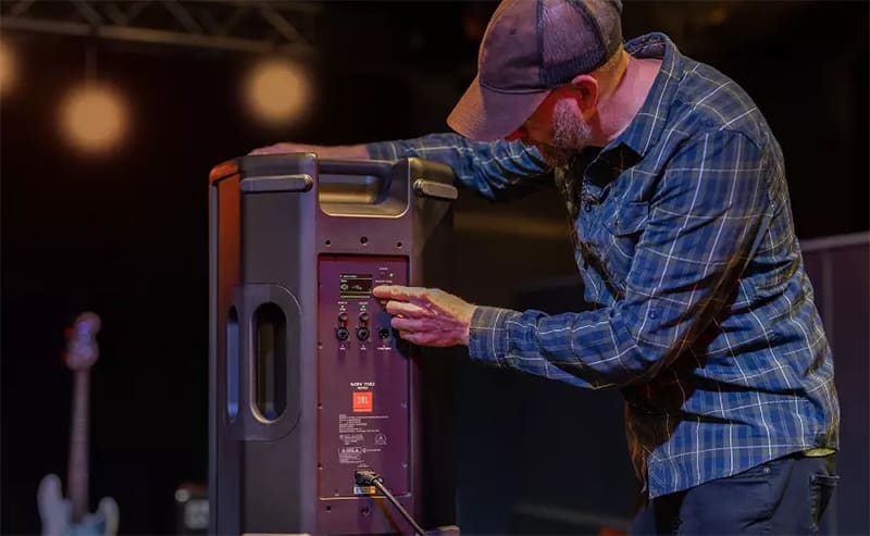 Man changing the settings on a JBL EON 710 loudspeaker.