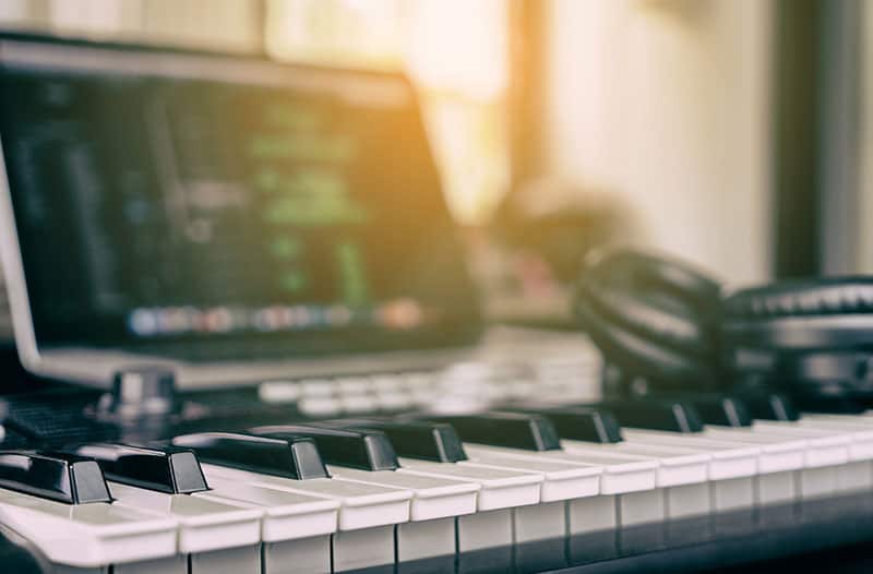 Keyboard and headphones with a laptop in the background