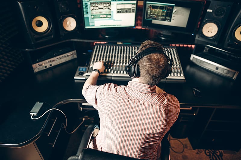 Sound engineer working in a small studio with audio equipment.