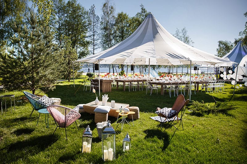 Outdoor wedding party tent and chairs near the water.