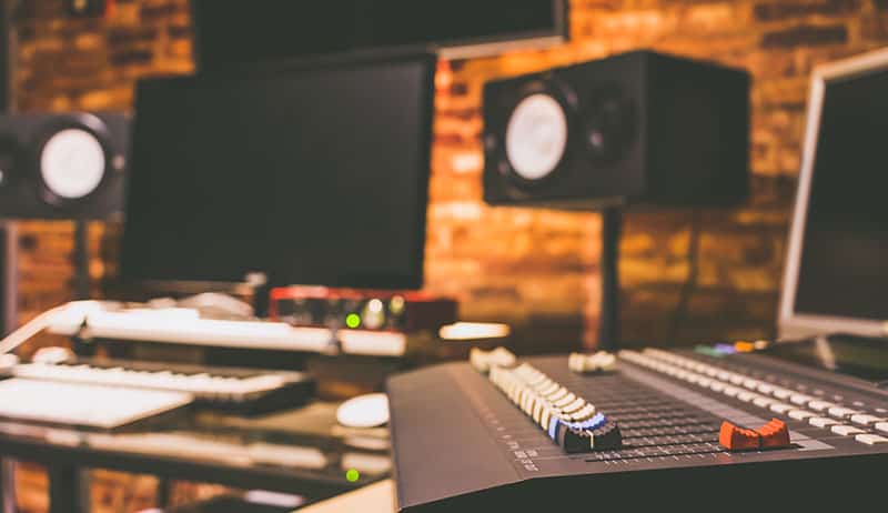 Photo of a music recording studio with studio monitors on stands.
