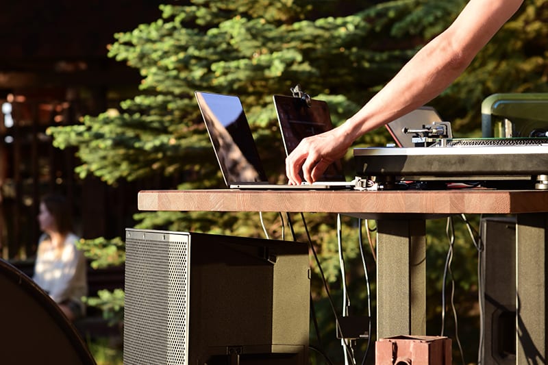 DJ performing outside with DJ speakers.
