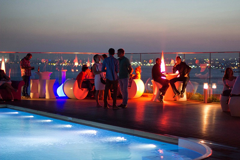 A bunch of people relaxing at a rooftop bar.