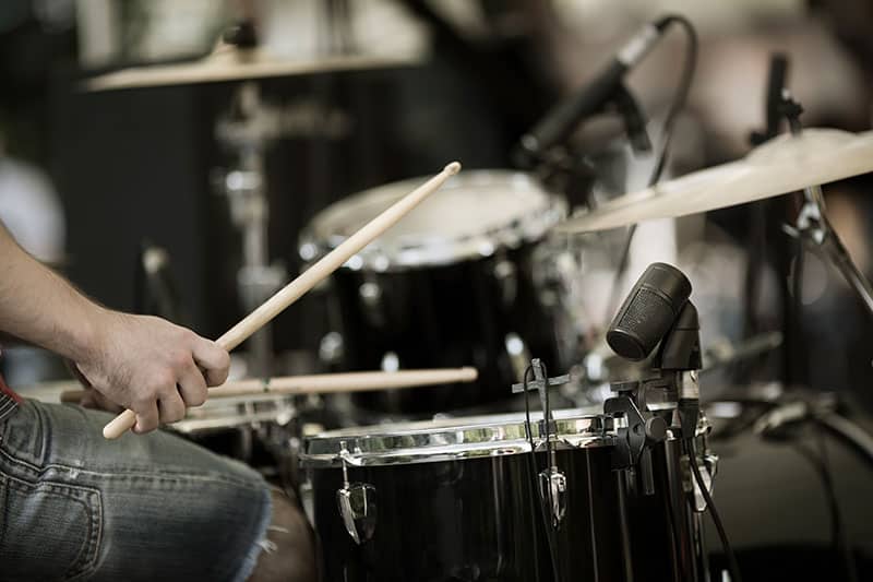 Drummer playing on drums with microphones recording.