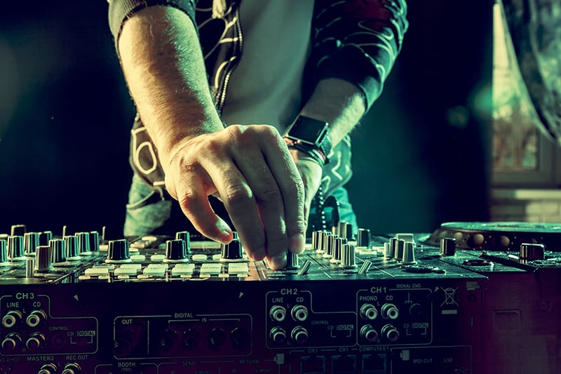 DJ adjusting EQ knobs on professional DJ gear