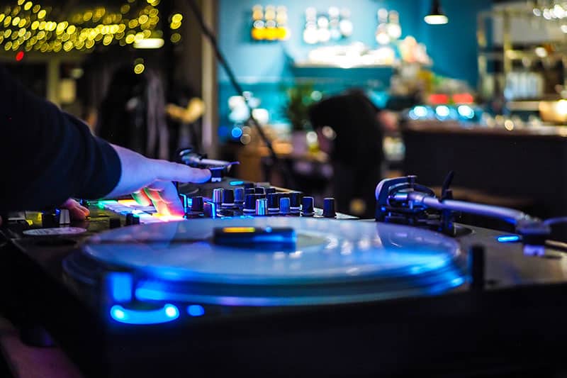 DJ playing at a bar using turntables and a mixer.