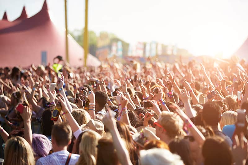 Crowd at a music festival with hands in the air.