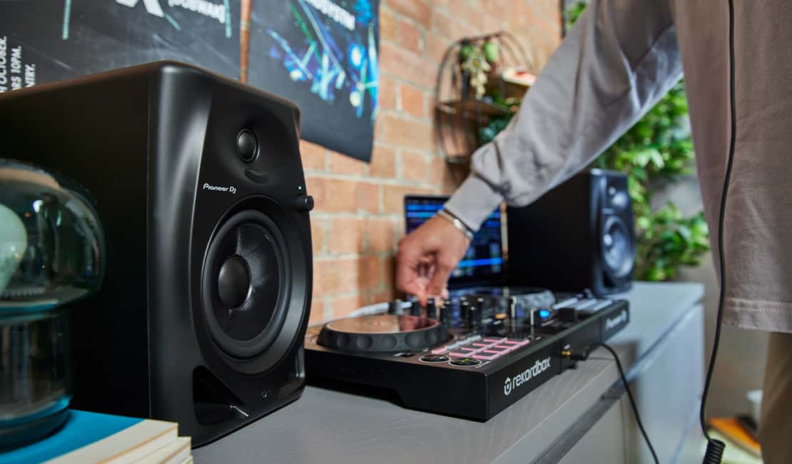 DJ using a DJ controller with Pioneer DM-50D monitors.