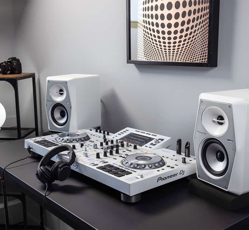 White Pioneer DJ VM-50 monitors next to a Pioneer DJ controller.