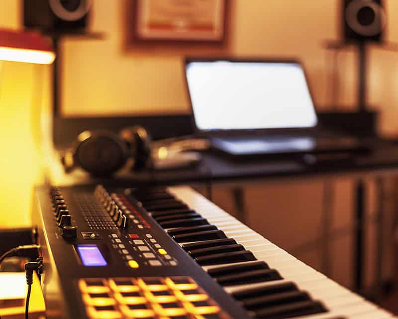 Music studio with laptop and headphones in the background and keyboard in the foreground