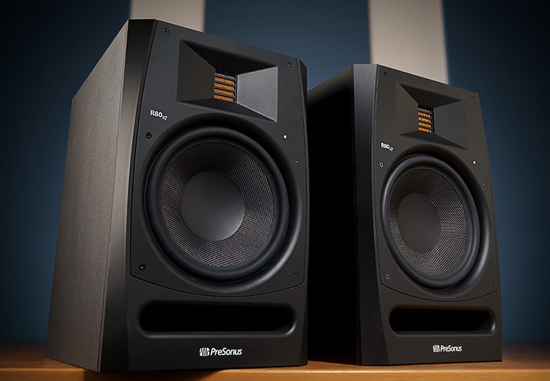 PreSonus R80 V2 monitors sitting on a wooden table.