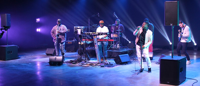 A band playing on stage with QSC K10.2 loudspeakers.