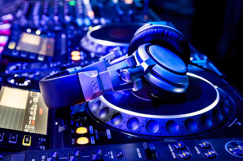 Photo of DJ headphones sitting on top of DJ equipment.