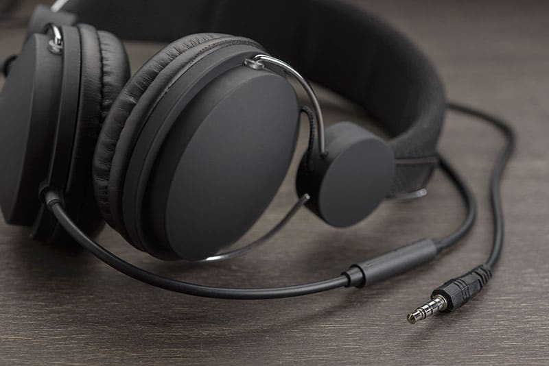 A pair of headphones on a dark wood grain desk.