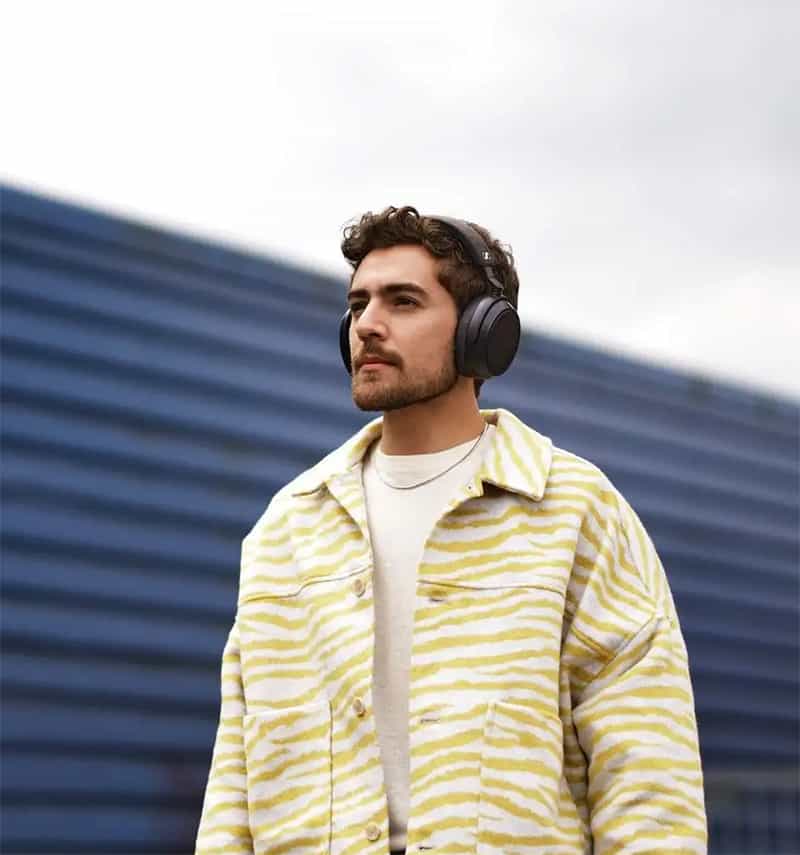 Man wearing Sennheiser Momentum 4 headphones.