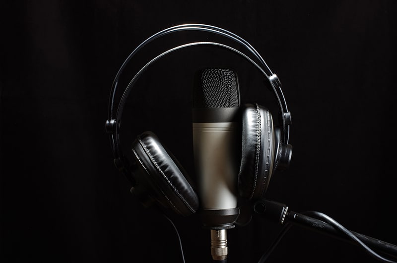 Headphones handing on a microphone with a black background.