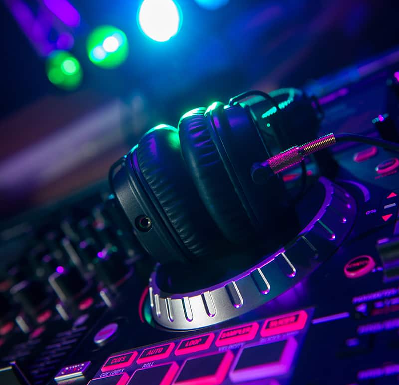 DJ headphones sitting on top of a DJ controller in a nightclub.