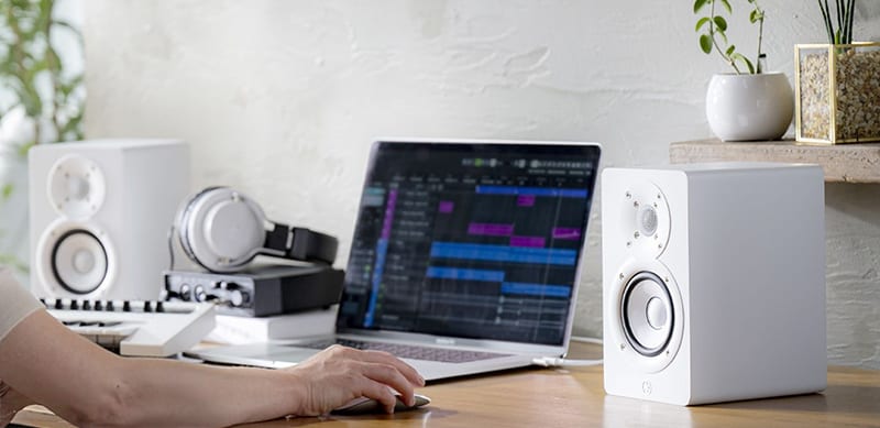 White Yamaha HS4 monitors sitting on a desk.