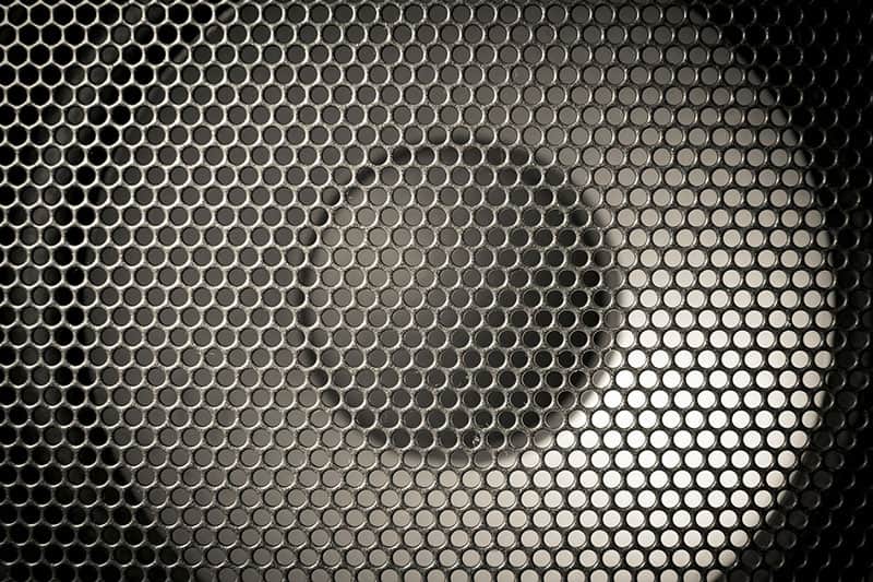 Close up photo of a woofer covered by a speaker grille
