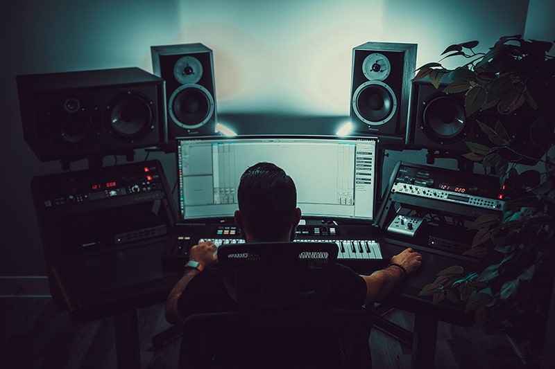Man sitting in a music studio with dim lighting.