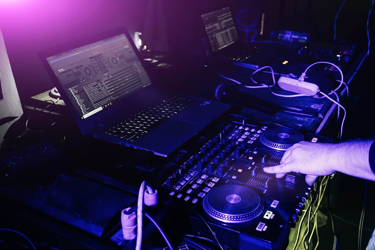 DJ using a DJ controller with a connected laptop.