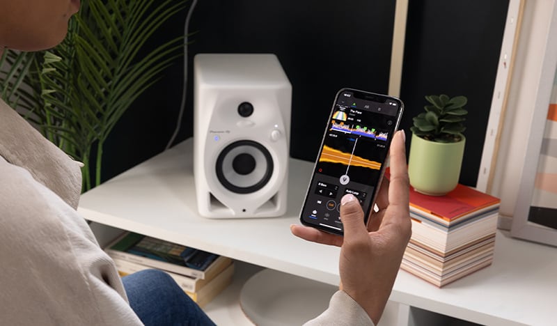 Person with a phone streaming music to a studio monitor in the background.