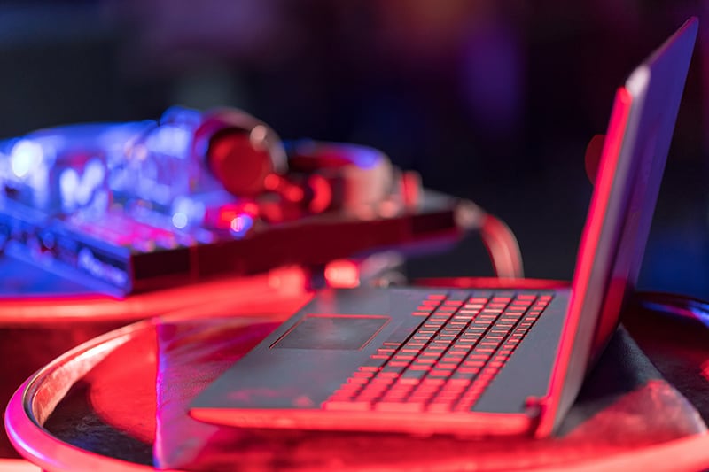 Laptop with DJ equipment in the background.