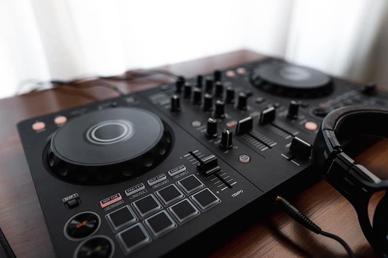 DJ controller sitting on a desk with headphones plugged in.