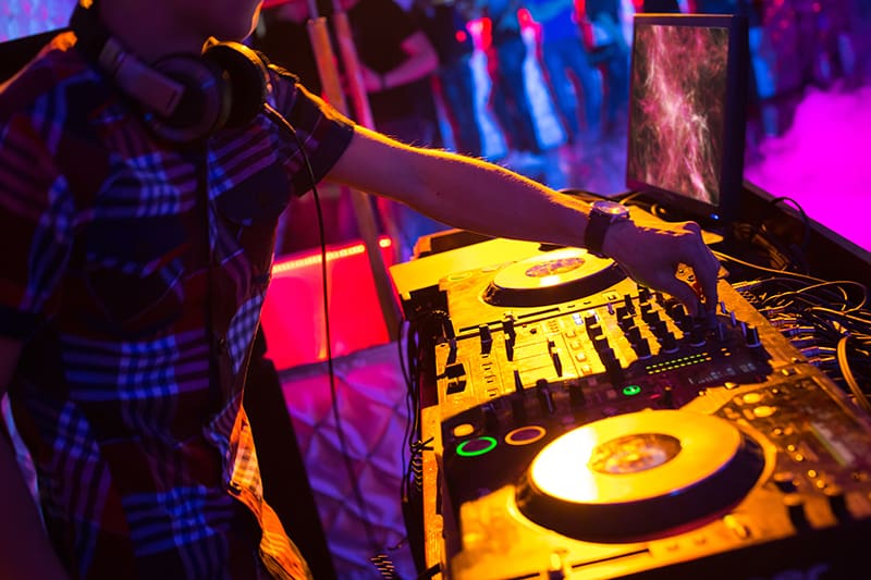 DJ mixing with his headphones around his neck.