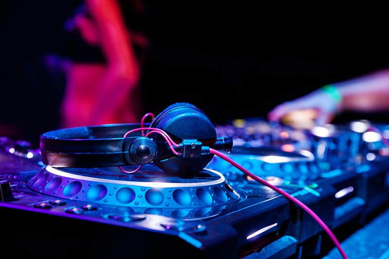 DJ headphones sitting on top of DJ equipment in a nightclub.
