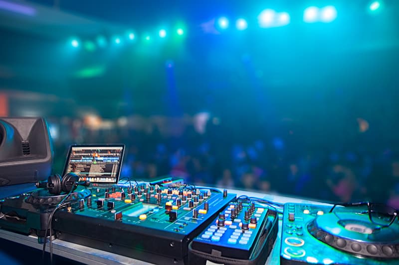 DJ Mixer and media players setup on a stage in front of a crowd.