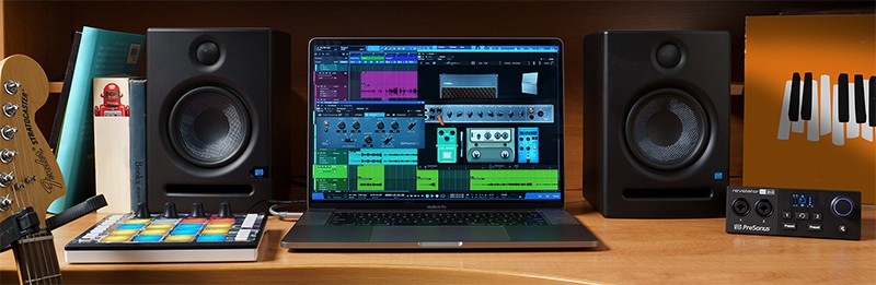 PreSonus monitors on a desk next to a laptop and other audio devices.
