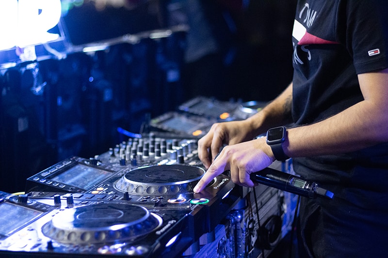 DJ holding a microphone while using DJ equipment.