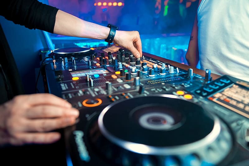DJ mixing on professional DJ equipment in a night club.