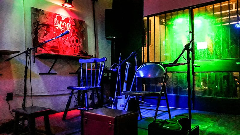 Photo of a small stage with chairs and microphones for performers