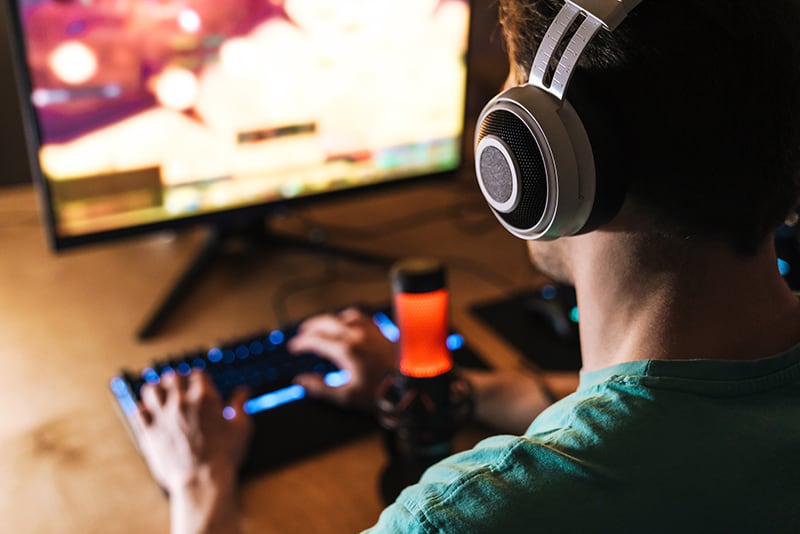 Man wearing semi-open headphones in front of a computer.