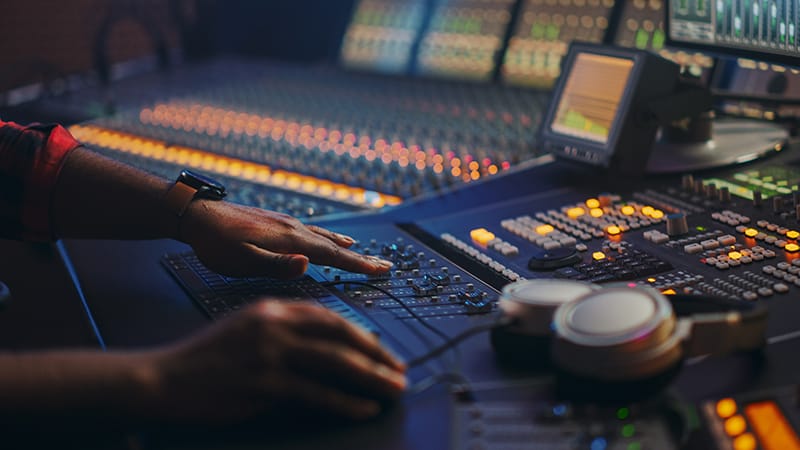 Mixing console in a music studio with headphones sitting on the console.