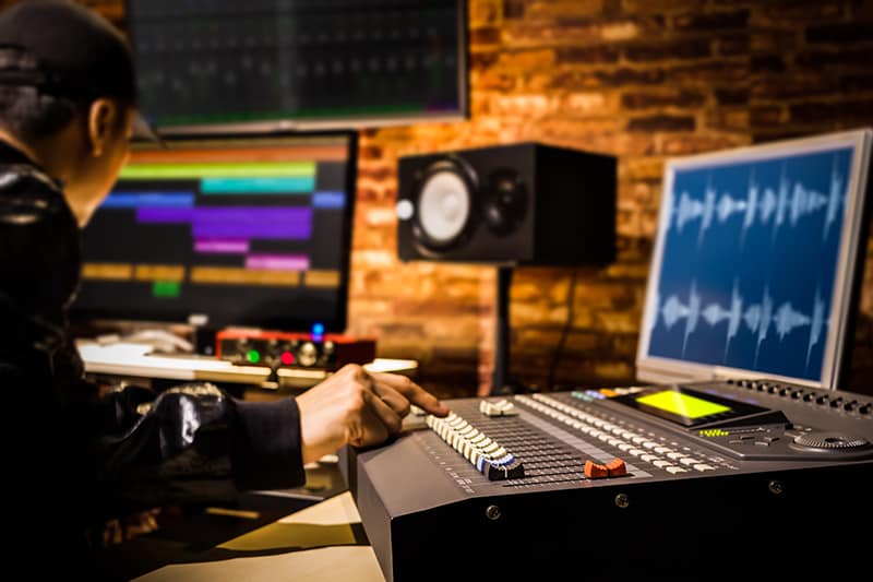 Music producer work on a track in a recording studio.