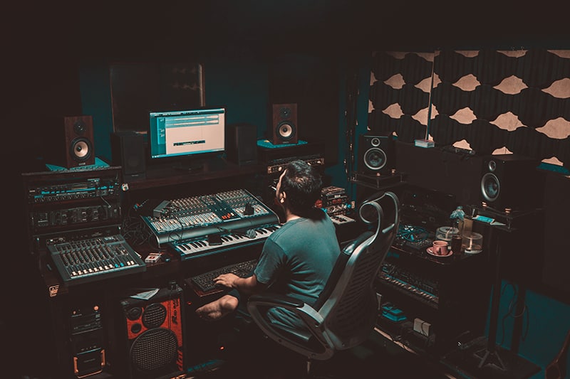 Man in a music studio with various pieces of music equipment.