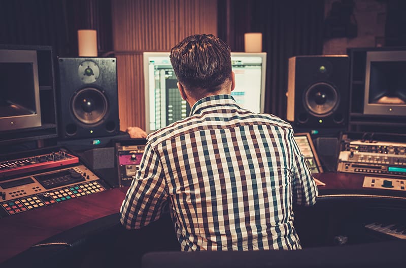 Man sitting in front of a monitor in a music studio.